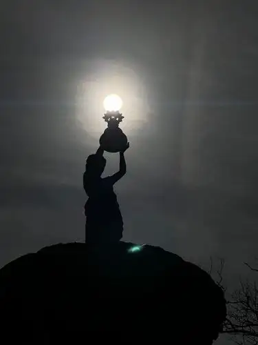 Holding the sun in her hands, a divine glow in the fading light.